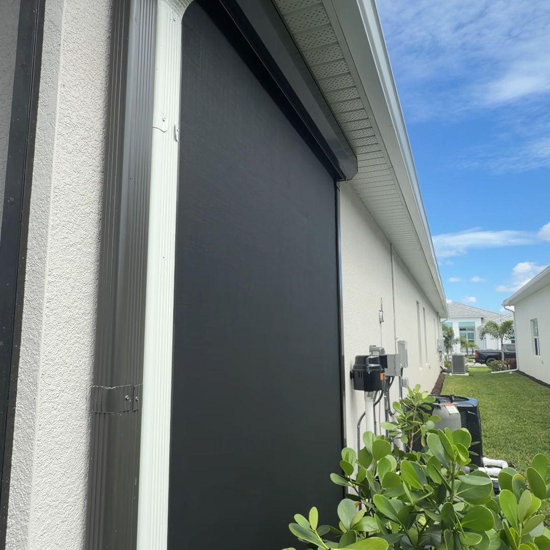 Lowered hurricane screen with its side track and housing beside a home