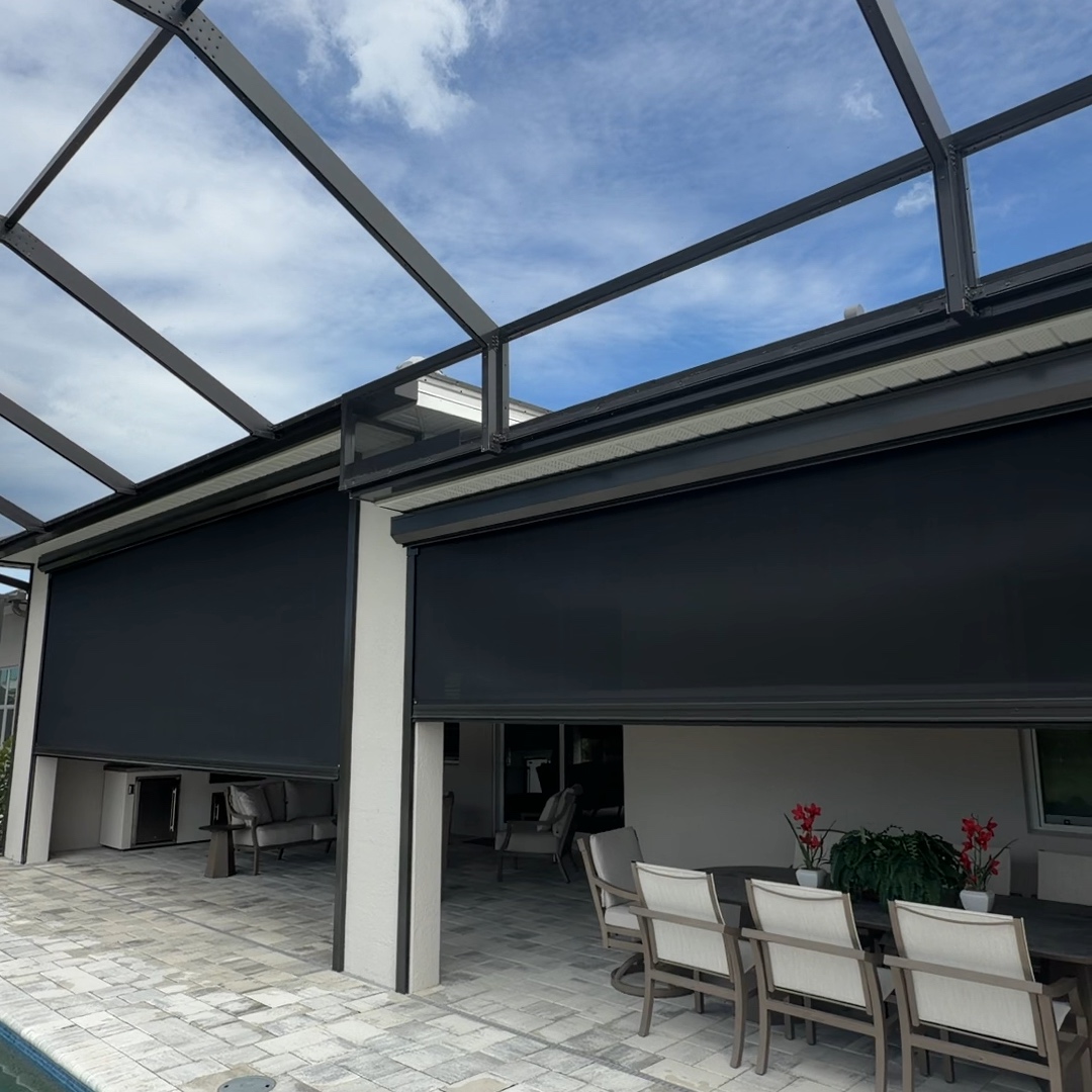 Partly lowered hurricane screens around a poolside lanai and dining area