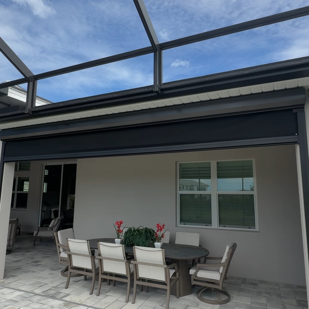 Partly lowered roll-down screen above a lanai dining table