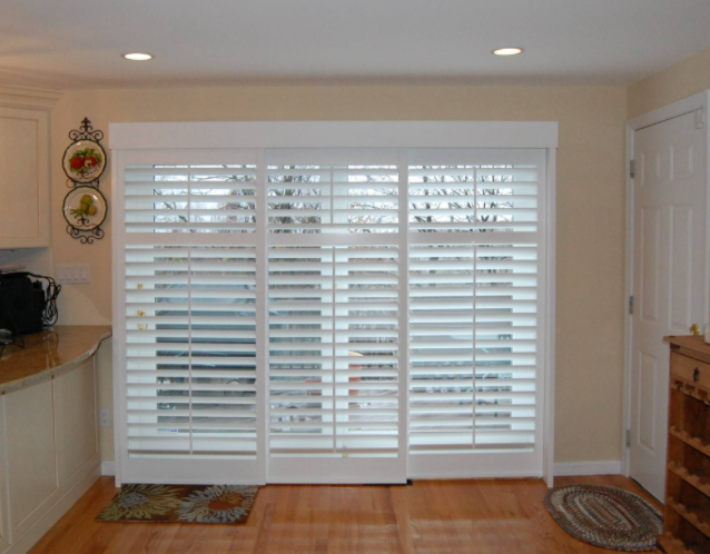 White bypass plantation shutters across a sliding glass door in a kitchen